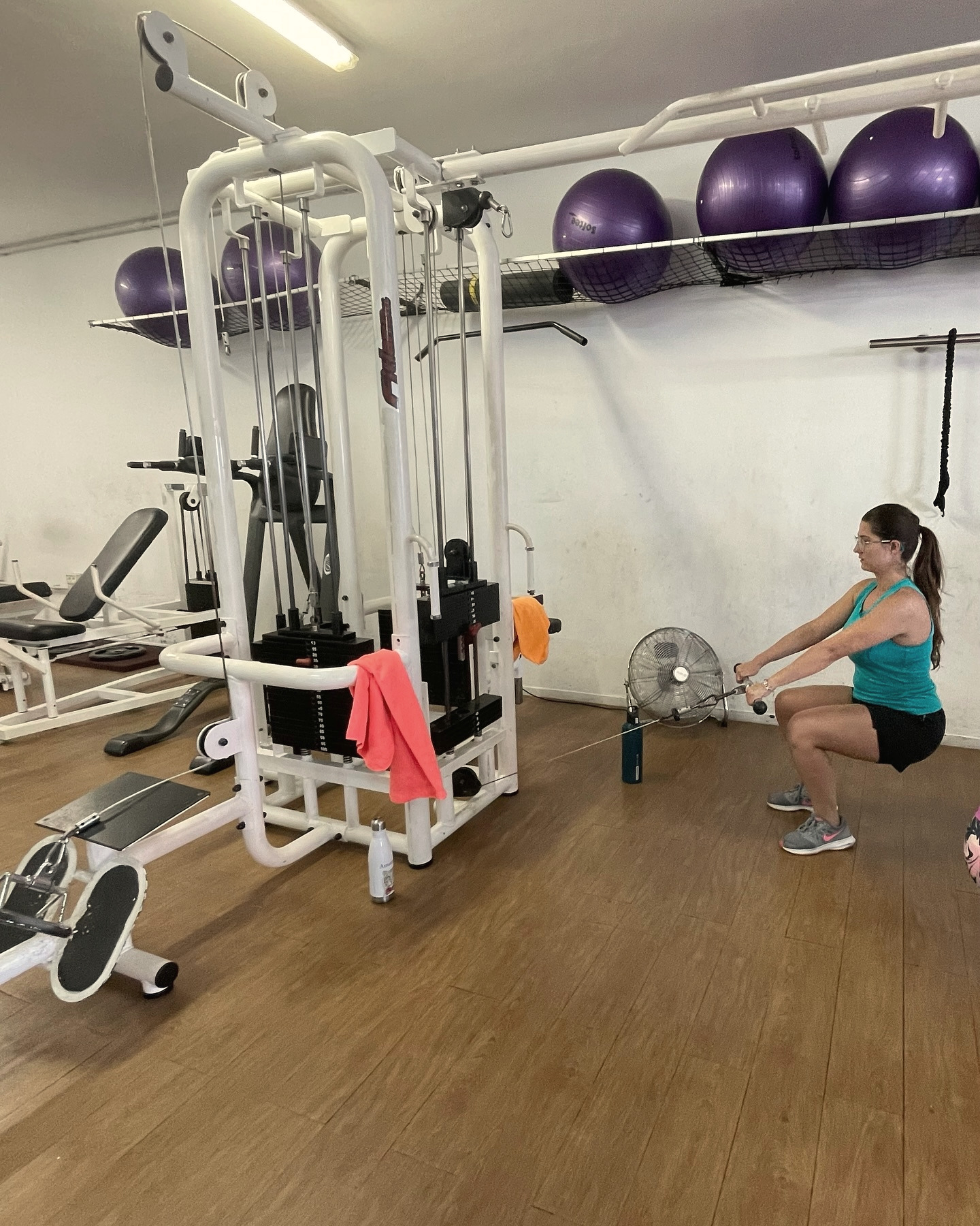 La sala de Féminas con los fitballs morados; al fondo, una mujer hace una sentadilla en la polea